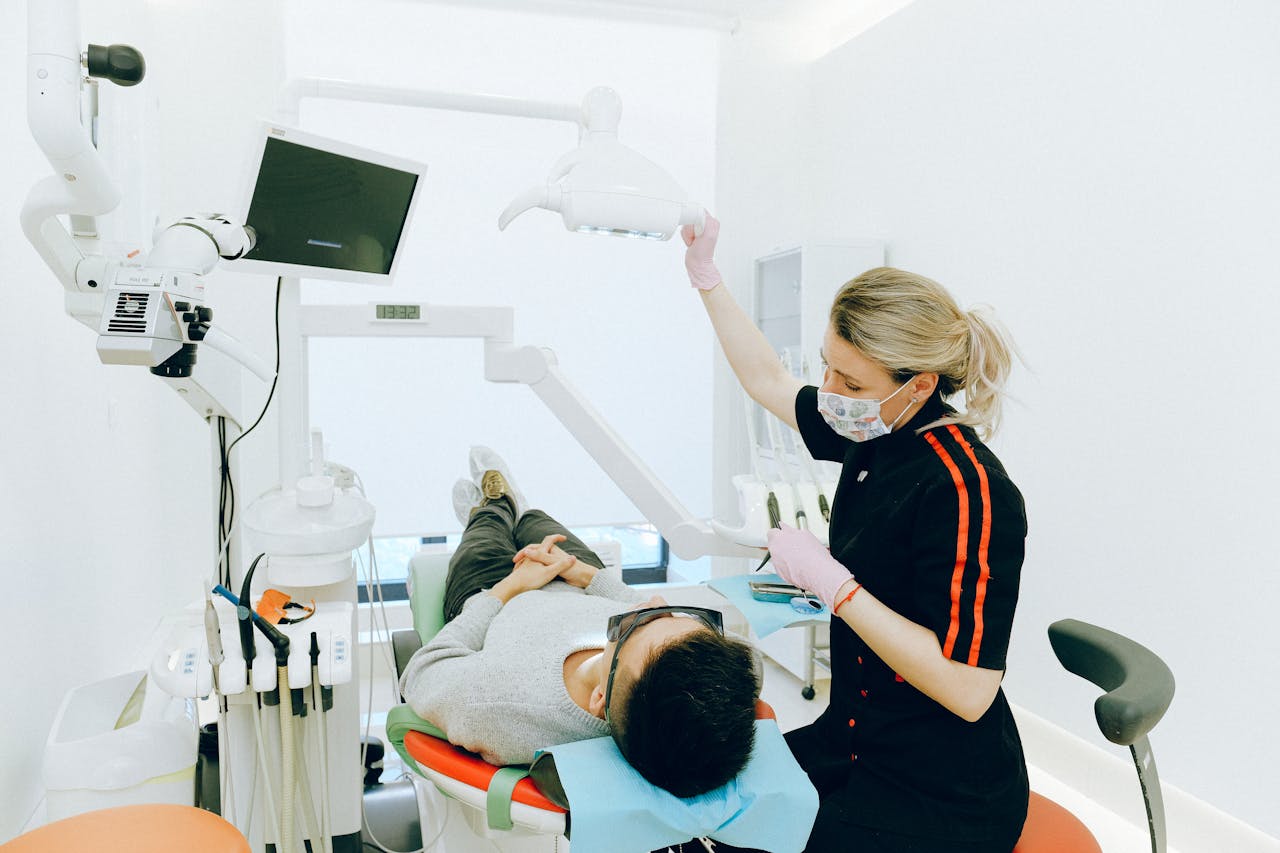 Female dentist examines patient's teeth in modern clinic setting.